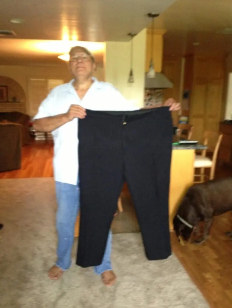 A man holding up his pants in the living room